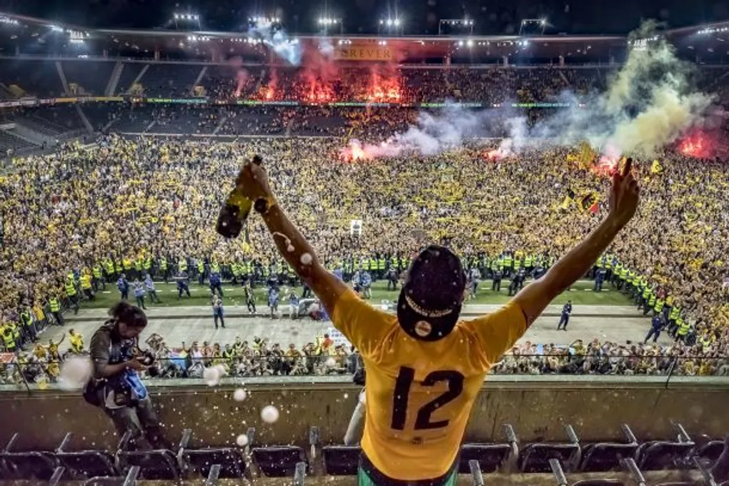 A Young Boys supporter celebrating in front of a pitch filled with fans after the club won the Swiss championship